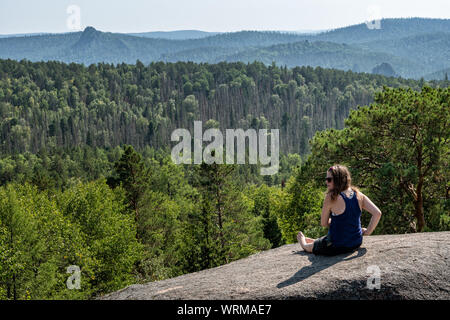 Giovane donna e la taiga dal quarto pilastro della Stolby Riserva Naturale, Siberia, Russia Foto Stock