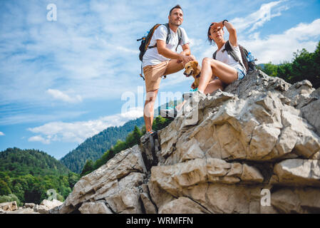 Escursionista giovane con cane in appoggio sul picco di montagna cercando di visualizzare Foto Stock