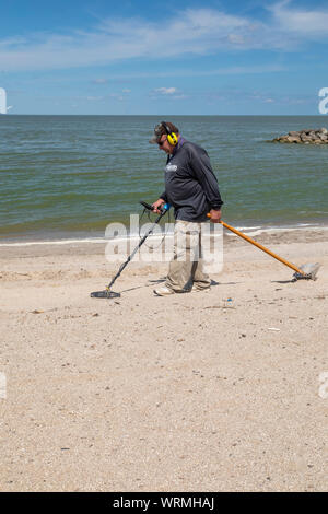 Oregon, Ohio - un uomo utilizza un rivelatore di metalli per la ricerca di monete e di altri metalli sulla spiaggia di Baia di Maumee parco dello stato. Foto Stock