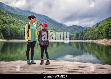 Madre e figlia in piedi sul molo presso il lago di montagna Foto Stock