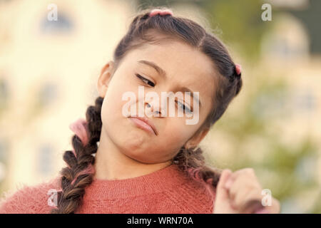 Essa ha bisogno di un buon parrucchiere. Carino bambina guardando lunghi capelli intrecciati. Kids parrucchiere. Parrucchiere per bambini. Facendo i suoi capelli come parrucchiere. Foto Stock