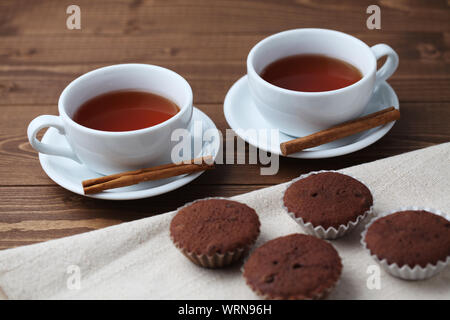 Tortini di cioccolato isolato su un tavolo di legno con tazza da tè Foto Stock