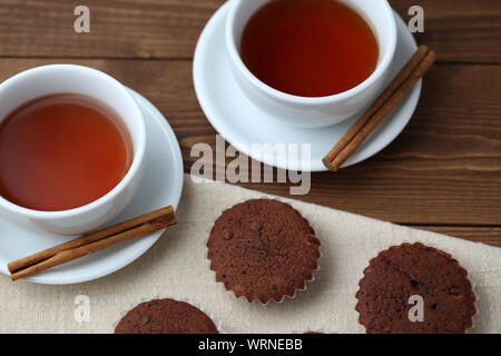 Tortini di cioccolato isolato su un tavolo di legno con tazza da tè Foto Stock