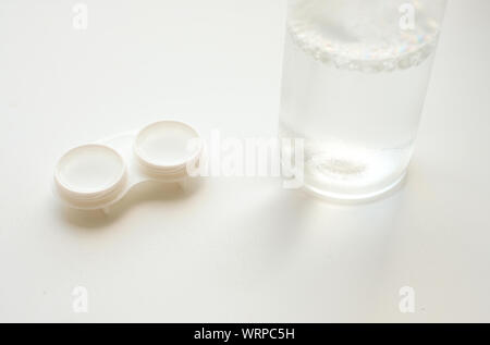 Accessori per l'uso corretto di lenti a contatto morbide: Custodia aperta e flacone di soluzione su sfondo bianco. Correzione sicura della visione. Messa a fuoco selettiva. Foto Stock