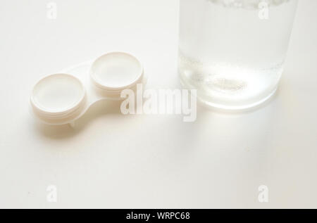 Accessori per l'uso corretto di lenti a contatto morbide: Custodia aperta e flacone di soluzione su sfondo bianco. Correzione sicura della visione. Messa a fuoco selettiva. Foto Stock