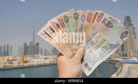 Un uomo tiene in mano il denaro degli Emirati Arabi. Canto close-up. Foto Stock