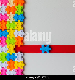 I colori di plastica puzzle jigsaw su carta bianca di sfondo, manca un puzzle sulla linea rossa per completare con copia spazio, strategia aziendale del lavoro di squadra Foto Stock