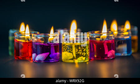 Piccole candele colorate su sfondo scuro Foto Stock