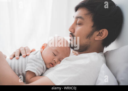 Simpatico bimbo che dorme sul padre al torace Foto Stock