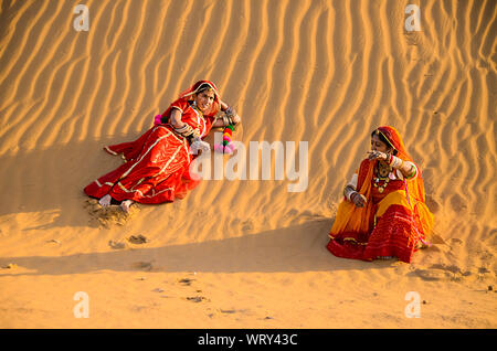 Jaisalmer, Rajasthan, India - aprile 18th, 2018: Villaggio Indiano le donne sedute in desert dune di sabbia etnica che indossa abiti tradizionali, la vita del villaggio conc Foto Stock