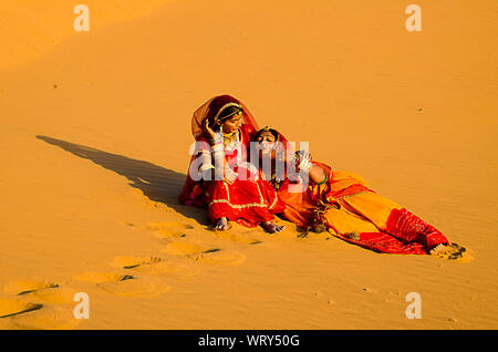 Jaisalmer, Rajasthan, India - aprile 18th, 2018: Villaggio Indiano le donne sedute in desert dune di sabbia etnica che indossa abiti tradizionali, la vita del villaggio conc Foto Stock