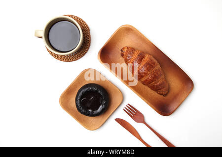 Croissant pane francese sul piatto di legno e il caffè caldo con dessert closeup isolati su sfondo bianco Foto Stock