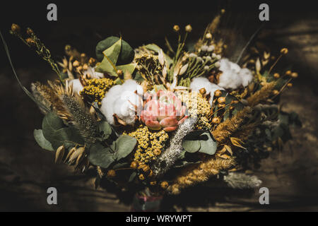 Bouquet nozze con fiori secchi. Cotone, succulenti spikelets di frumento e di altri. Sfondo scuro. Foto Stock