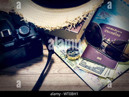 Concetto di viaggio con la fotocamera digitale, cappello di paglia, libro, mappa, bussola, passaporto, denaro e gli occhiali da sole sul tavolo di legno Foto Stock