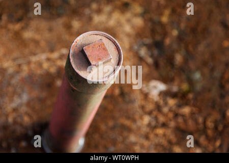 Rusty tubo di ferro che è bloccato nel terreno e si erge a diritto fino alla sommità del tubo vi è una parte avvitabile che è rettangolare Foto Stock