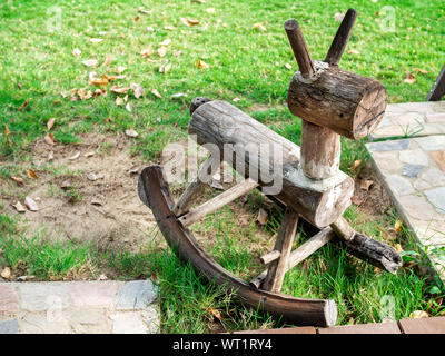 In legno cavallo a dondolo realizzato dal vecchio legno sull'erba verde. Foto Stock