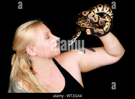 Ritratto di ragazza con Royal Python snake. Bella donna serpente tiene nelle mani e in posa nella parte anteriore della fotocamera. Foto Stock