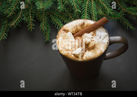 Natale tradizionale bevanda. Cioccolata calda con marshmallows e cannella su sfondo nero con albero di natale ramo. Holiday card. Close up. Foto Stock