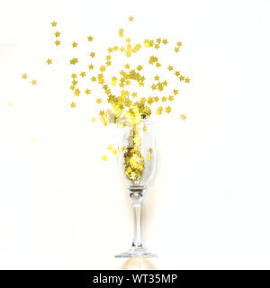 Coriandoli a forma di stelle effuso bicchieri di champagne su uno sfondo bianco. Vista dall'alto. Foto Stock