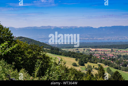 Panorama della città nelle montagne, colline, campi, foreste e prati verdi, laghi in lontananza e il cielo blu con nuvole.Town Bons-en-Chablais in Francia. Foto Stock