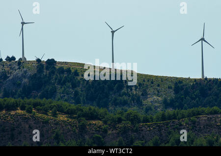 Tre turbine eoliche sulla cima di una montagna boscosa contro un cielo pallido (Rhodes, Grecia) Foto Stock