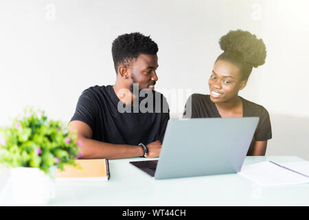 Diversi colleghi seduti ad una scrivania in un ufficio moderno parlare insieme su un computer portatile Foto Stock