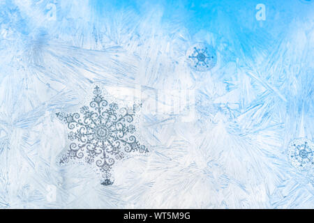 Vignetta di fiocchi di neve sul ghiaccio vetro smerigliato con vetro blu cielo visto in background. L'immagine orizzontale con spazio di copia Foto Stock