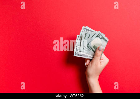 Un pacco di banconote da cento dollari in mano femmina su sfondo colorato. Concetto di stipendio con copia spazio. Foto Stock