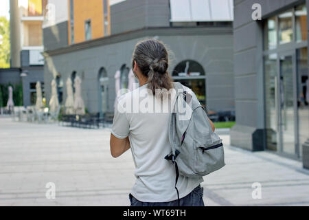 Uomo di mezza età con zaino grigio sulla strada; con spazio di copia Foto Stock