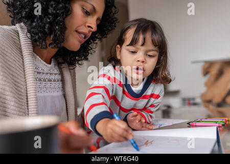 Madre premurosa e la sua adorabile bambina la colorazione a casa Foto Stock