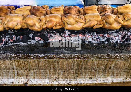Pollo alla griglia fila sul metallo spiedino è la cottura sulla pila di carbone nel mercato tailandese Foto Stock