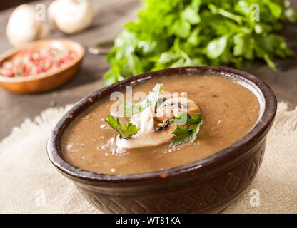 Deliziosa cremosa zuppa di funghi con prezzemolo e close-up su sfondo scuro. Foto Stock