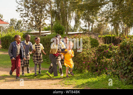 Imani Junior Academy, Nanyuki, contea di Laikipia, Kenya - Giugno 13th, 2019: Candida fotografia della scuola di giovani bambini che giocano con una ragazza di colore bianco che è stato Foto Stock