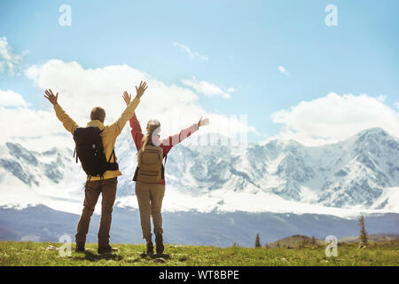 Due escursionisti di successo si erge contro montagne bianche con le mani alzate Foto Stock