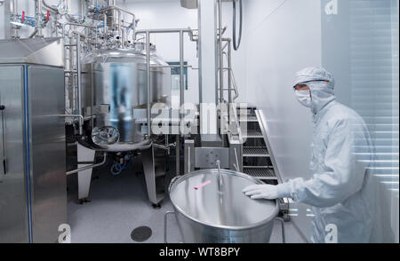 11 settembre 2019, Sassonia-Anhalt, Dessau-Roßlau: un dipendente di Merz Pharma lavora in una camera pulita della società su un gel lo strato di miscela. A livello globale la società operativa ha investito 15 milioni di euro nel nuovo impianto di produzione per la fabbricazione di dermal riempitivi a base di acido ialuronico per uso in medicina estetica. Merz impiega attualmente circa 150 persone presso la sua sede in BioPharmaPark Dessau-Roßlau. Foto: Hendrik Schmidt/dpa-Zentralbild/ZB Foto Stock