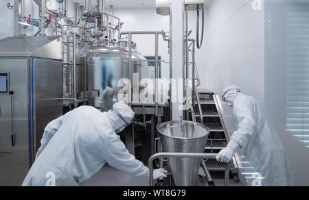 11 settembre 2019, Sassonia-Anhalt, Dessau-Roßlau: i dipendenti di Merz Pharma opera in una camera pulita della società su un gel di impianto di miscelazione. A livello globale la società operativa ha investito 15 milioni di euro nel nuovo impianto di produzione per la fabbricazione di dermal riempitivi a base di acido ialuronico per uso in medicina estetica. Merz impiega attualmente circa 150 persone presso la sua sede in BioPharmaPark Dessau-Roßlau. Foto: Hendrik Schmidt/dpa-Zentralbild/ZB Foto Stock