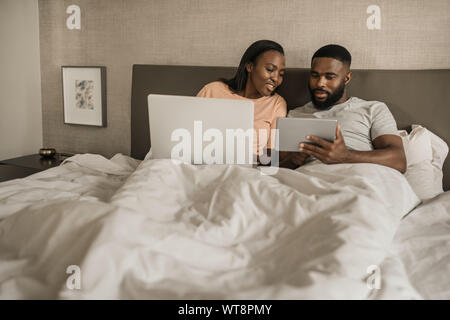African American giovane che giace nel letto di controllare le loro social media Foto Stock