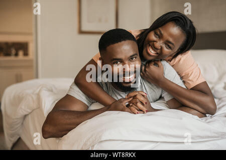Sorridente giovane africano coppia americana giocando a letto insieme Foto Stock
