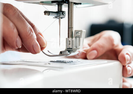 Donna di mano azienda thread threading e un ago della macchina da cucire Foto Stock