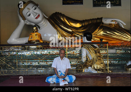 21.01.2014, Yangon, Myanmar, Asia - un uomo medita di fronte ad una statua di Buddha nel tempio composto della Shwedagon pagoda. Foto Stock