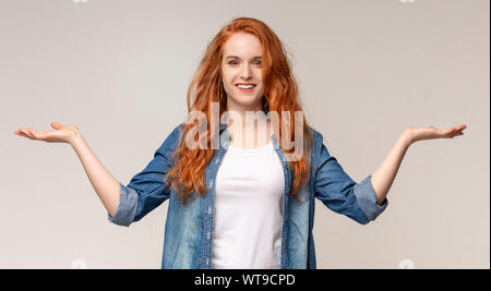 Ragazza giovane confrontando varianti, rendendo le scale con le sue mani vuote Foto Stock