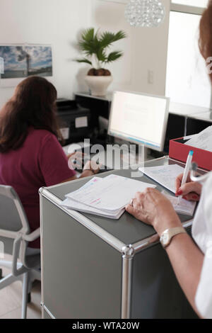 Medico a scrivere gli appuntamenti giornalieri presso la reception della moderna pratica medica Foto Stock