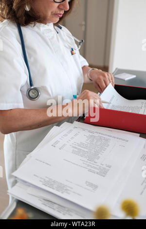 Medico donna sorting out dei file del paziente e documenti Foto Stock