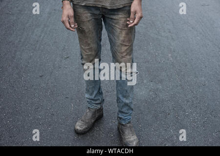Uomo al lavoro con vestiti molto sporchi Foto Stock