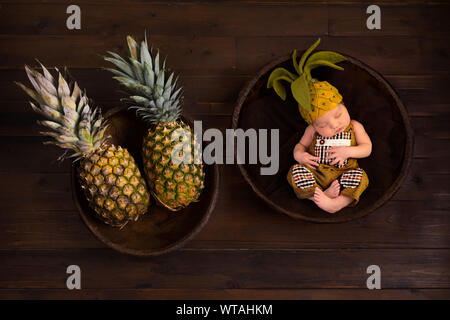 Carino immagine composita con ananassi freschi e un neonato in feltro ananas hat Foto Stock