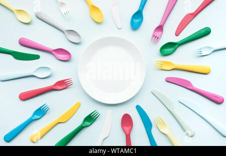 Vista superiore del piatto con il cucchiaio colorato e elemento a forcella sulla tavola a colori.piatto design dei laici Foto Stock