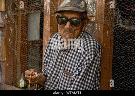 Blind vecchio uomo che prega per le strade tenendo un japamala Foto Stock