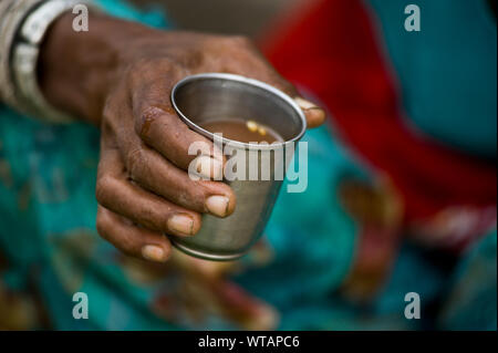 Donna di Rajasthani tenendo un bicchiere di metallo di masala chai Foto Stock