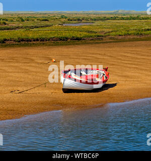 Barca spianata sulla sabbia a bassa marea a Burnham-Overy-Staithe sulla costa di Norfolk, Inghilterra, Regno Unito Foto Stock