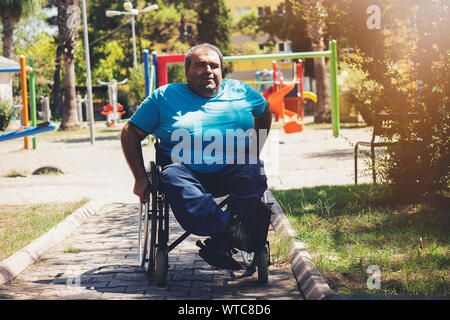 Uomo disabili in carrozzella walking park Foto Stock